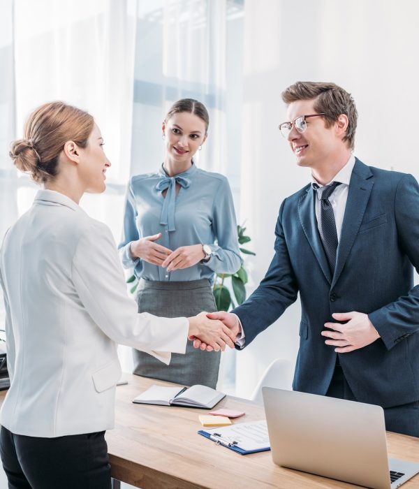 cheerful-recruiter-shaking-hands-with-woman-near-colleague-in-office.jpg